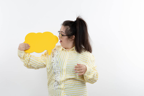 κορίτσι με σύνδρομο down ποζάρουν με κίτρινη φούσκα ομιλία κοπεί χαρτί - Φωτογραφία, εικόνα