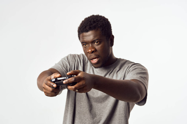 Vrolijke man van Afrikaanse verschijning met een joystick in zijn handen speelt video games - Foto, afbeelding