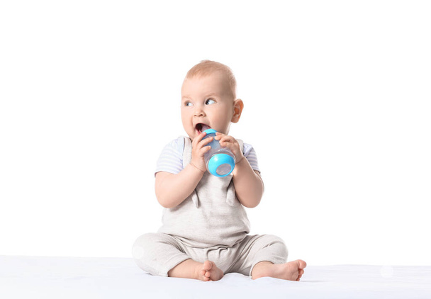 Cute little baby drinking water from bottle on white background - Photo, Image