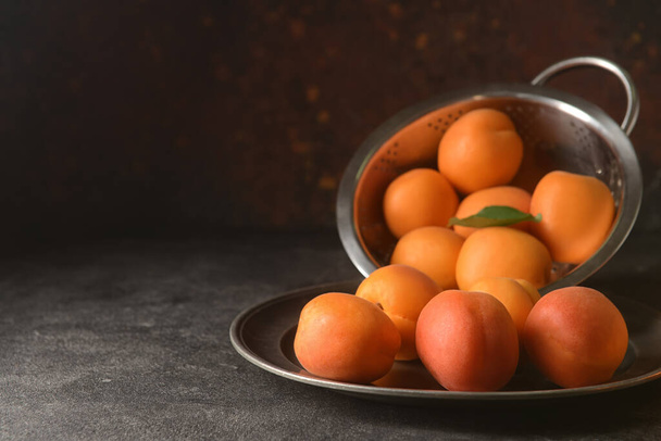 Plate with tasty ripe apricots on dark background - Фото, зображення