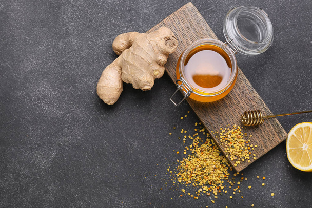 Jar of honey with bee pollen, ginger and lemon on dark background - Fotografie, Obrázek