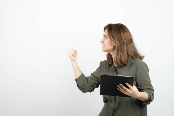 Portrait of young adorable woman with clipboard arguing with someone. High quality photo - Photo, Image