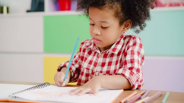 Africké děti kreslou a dělají domácí úkoly v učebně, mladá dívka je šťastná a hraje si na papíře na základní škole. Dětský kreslením a malování na školní koncepci. - Fotografie, Obrázek
