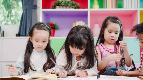 Group of children drawing in classroom, Multi-ethnic young boys and girls happy funny study and play painting on paper at elementary school. Kids drawing and painting at school concept. - Photo, Image