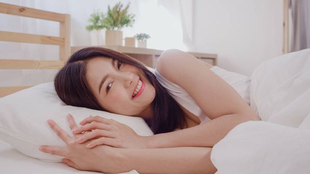 Asian woman smiling lying on bed in bedroom, Beautiful japanese female using relax time after wake up at home. Lifestyle women using relax time at home concept. - Photo, Image
