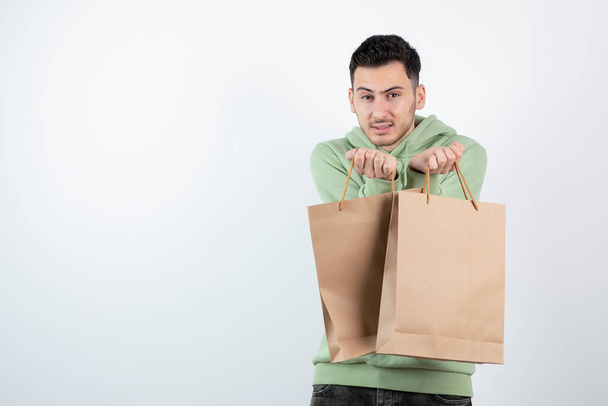 Handsome man in green hoodie holding paper bags. High quality photo - Foto, afbeelding
