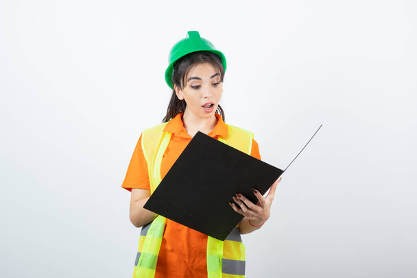Kobieta inżynier w kasku ochronnym i żółta kamizelka z folderem. Wysokiej jakości zdjęcie - Zdjęcie, obraz