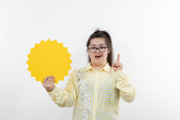 девушка с синдромом Дауна позирует с желтым солнцем фигурка вырезать бумагу - Фото, изображение