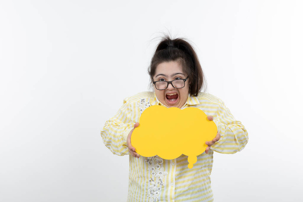 Mädchen mit Down-Syndrom posiert mit gelbem Sprechblasenpapier - Foto, Bild