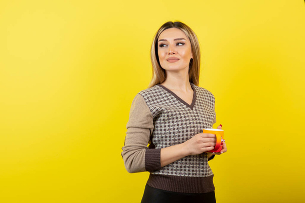 belle femme posant avec tasse sur fond jaune - Photo, image