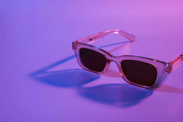 Stylish female sunglasses on color background - Fotó, kép
