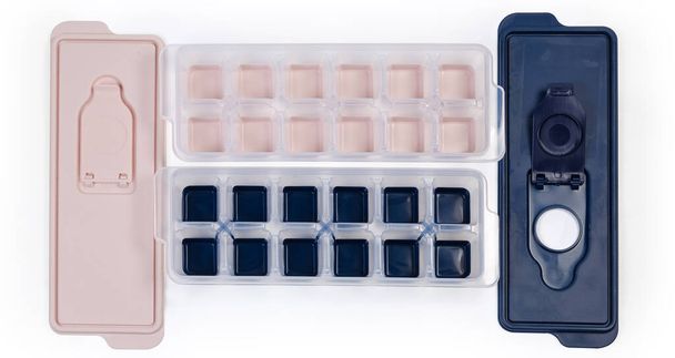 Two open household molds different colors for ice cube making and removed lids on a white background, top view - Photo, Image