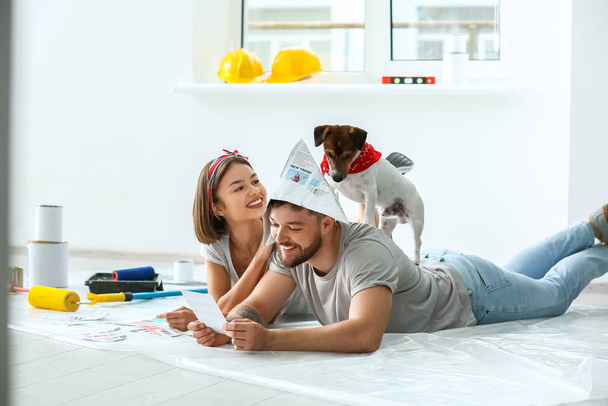 Young couple with cute dog and palette samples planning design of their new house - 写真・画像