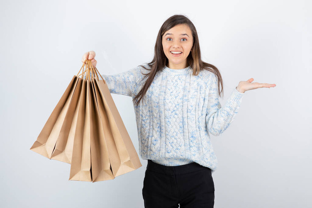 Portrait of teen girl in sweater holding shopping bags - Фото, изображение