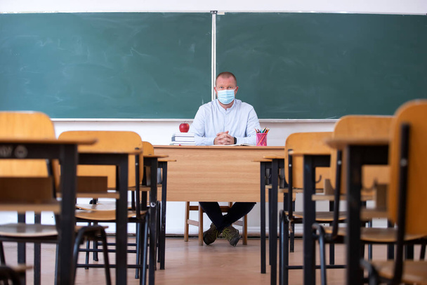  Teacher with mask in the classroom. Social distanting and classroom safety during coronavirus epidemic - Photo, Image