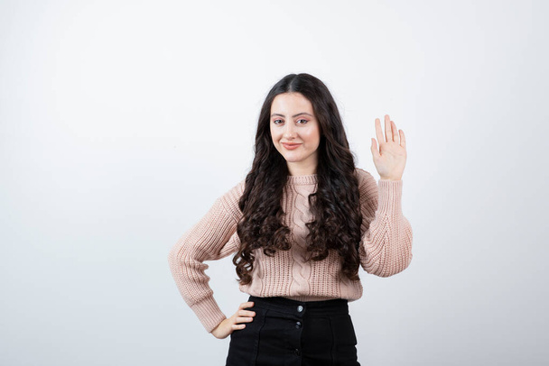 Image of beautiful woman waving hand against white wall . High quality photo - Photo, Image