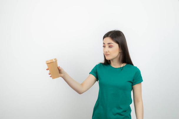 Fiatal, gyönyörű barna nő kezében egy pohár kávé. Kiváló minőségű fénykép - Fotó, kép