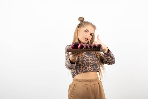 Beautiful woman in crop top holding plate of red onions. High quality photo - Photo, Image