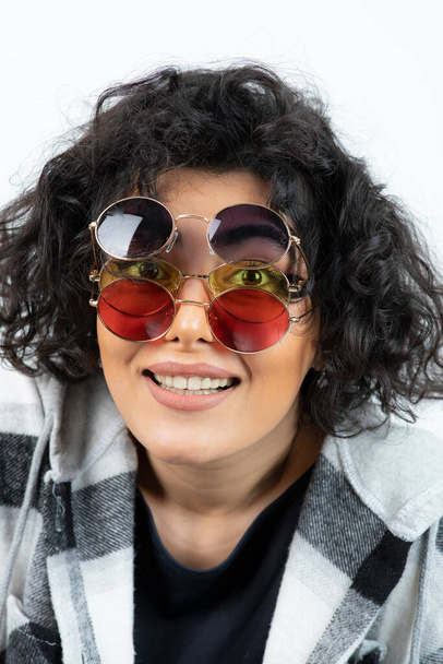 Fashion portrait woman with curly hair posing in stylish glasses over a white wall . High quality photo - Foto, Imagem
