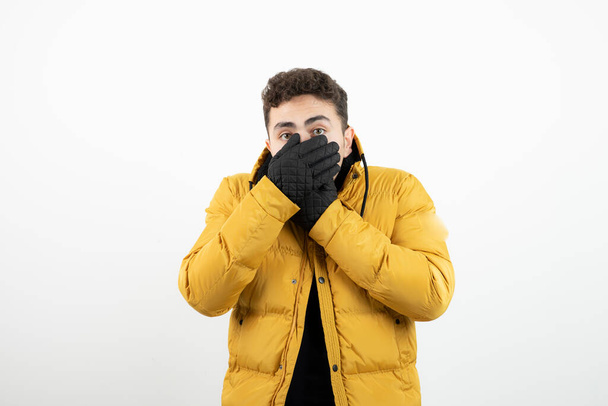 Young guy in winterwear and gloves trying to warm his hands . High quality photo - 写真・画像