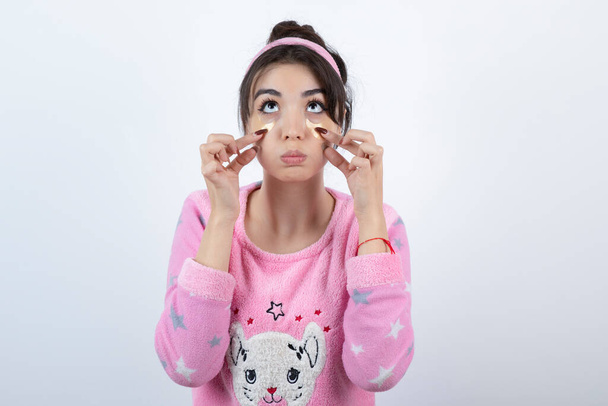 Foto de uma jovem no pijama usando manchas nos olhos. Foto de alta qualidade - Foto, Imagem
