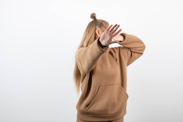 Portrait of female blonde model standing and covering her face. High quality photo - Photo, image