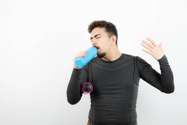 Image of a young sporty man model holding colorful bottles of water. High quality photo - Foto, afbeelding