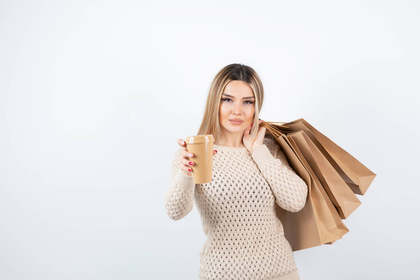Image of nice-looking woman standing and holding paper bags with cup . High quality photo - Photo, Image