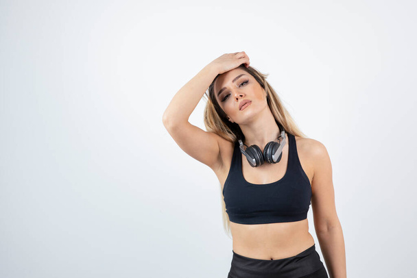 gyönyörű fiatal nő sportos ruhában pózol fejhallgatóval a nyakán - Fotó, kép