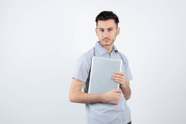 Portrait of young student with laptop standing over white wall. High quality photo - Photo, Image