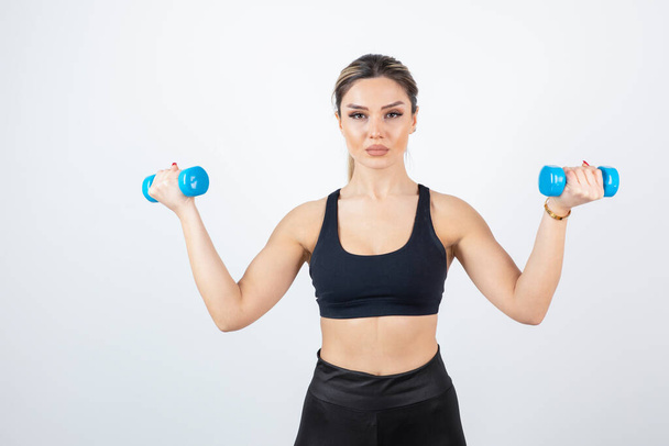 beautiful young woman in sportive clothes with dumbbells - Fotografie, Obrázek