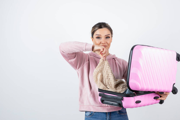 Young pretty model with pink suitcase holding jacket. High quality photo - Photo, Image