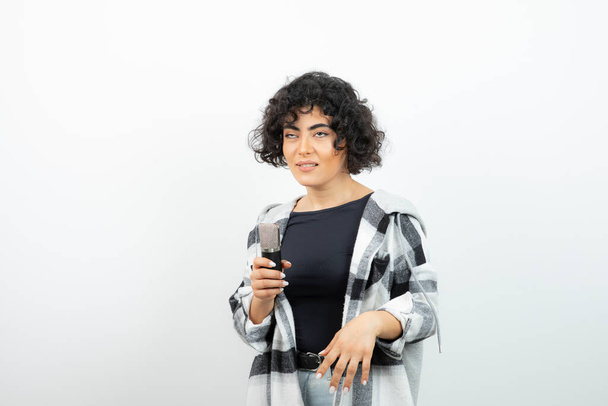 Портрет молодої брюнетки з кошлатою зачіскою, що тримає мікрофон. Високоякісна фотографія
 - Фото, зображення