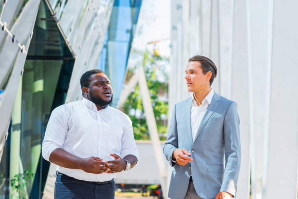 African-American businessman and his colleague in front of modern office building. Financial investors are talking outdoor. Banking and business concept. - Фото, зображення