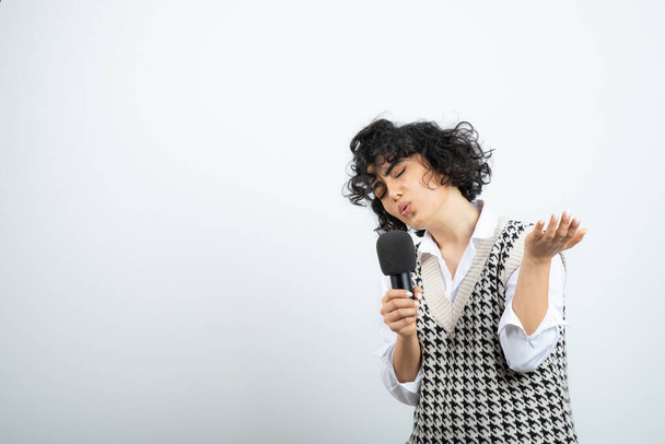 Photo of curly brunette woman singing by heart with microphone. High quality photo - Photo, Image