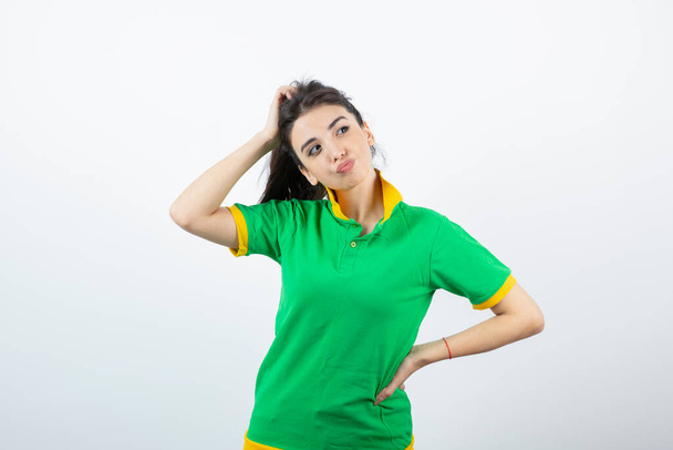 Image of young brunette girl in green t-shirt thinking about something. High quality photo - Photo, Image