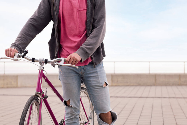 unrecognizable young man walking with a vintage bike, concept of sustainable transportation and urban lifestyle, copy space for text - Photo, image