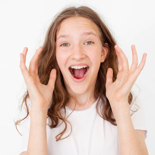 Cheerful happy young beautiful girl looking at camera smiling laughing over white background. Happy teen  in white t-shirt Winner - Foto, Bild