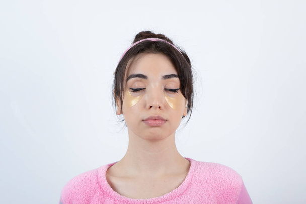 Foto de uma jovem no pijama com manchas oculares em pé com os olhos fechados. Foto de alta qualidade - Foto, Imagem