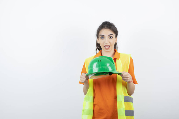 Female worker construction in vest showing hardhat to camera . High quality photo - Zdjęcie, obraz