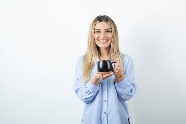 Portrait of happy woman holding cup of hot drink against white wall. High quality photo - Foto, Imagen