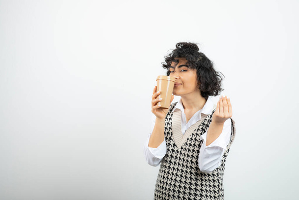 Φωτογραφία της όμορφης γυναίκας που δείχνει νόστιμη χειρονομία και κρατώντας ένα φλιτζάνι καφέ. Υψηλής ποιότητας φωτογραφία - Φωτογραφία, εικόνα