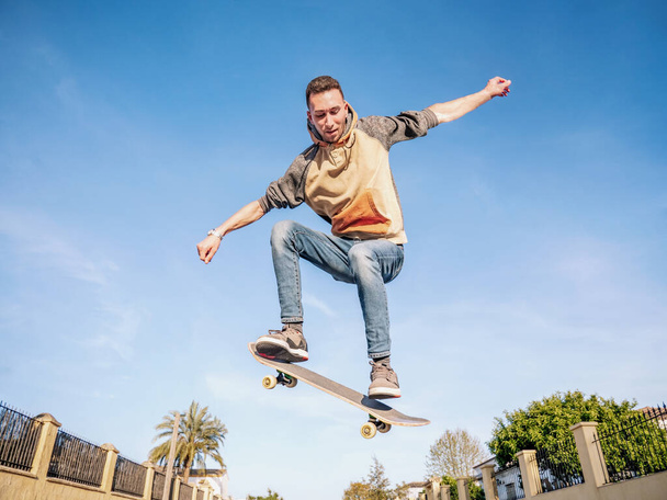 Молодой человек прыгает на скейтборде на улице. Селективный фокус - Фото, изображение
