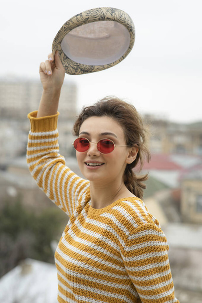 Una joven linda mujer sosteniendo una gorra y posando en el exterior. Foto de alta calidad - Foto, imagen