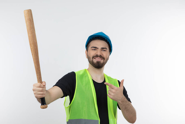 Fusillade d'un jeune ouvrier en casque tenant une batte de baseball. Photo de haute qualité - Photo, image