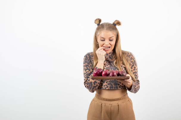 Pretty woman in crop top holding plate of red onions and standing. High quality photo - Fotó, kép