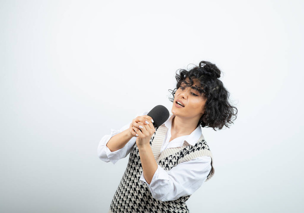 Photo of curly brunette woman singing by heart with microphone. High quality photo - Photo, Image