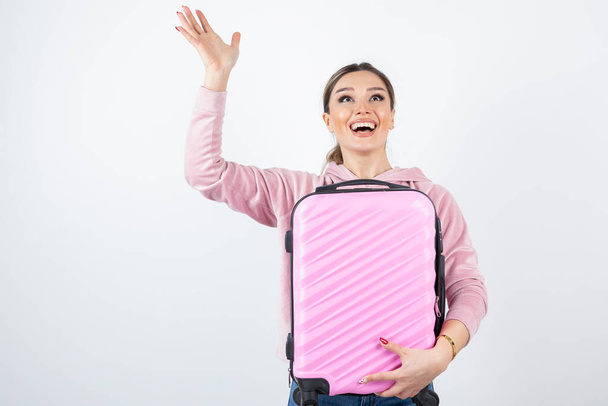 Image of attractive woman in pink hoodie holding suitcase. High quality photo - Foto, imagen
