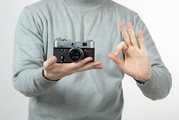 Αρσενικός επαγγελματίας φωτογράφος χέρια κρατώντας ρετρό κάμερα και κάνει εντάξει σημάδι. Υψηλής ποιότητας φωτογραφία - Φωτογραφία, εικόνα