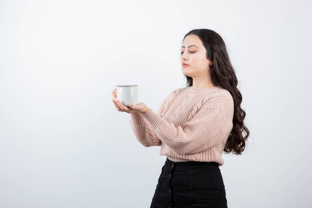 Joven morena sosteniendo una taza de café caliente sobre fondo blanco. Foto de alta calidad - Foto, imagen